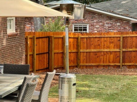 Fence stained in Cedar behind a patio dining area