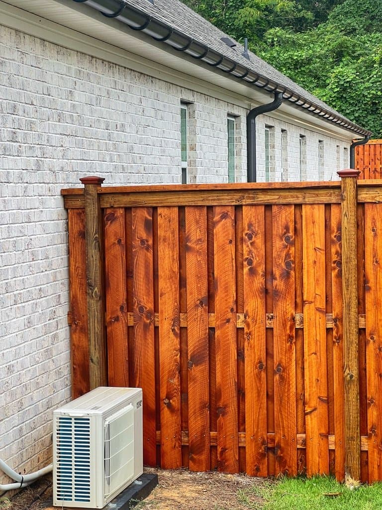 Privacy fence stained in Pecan beside a white brick home